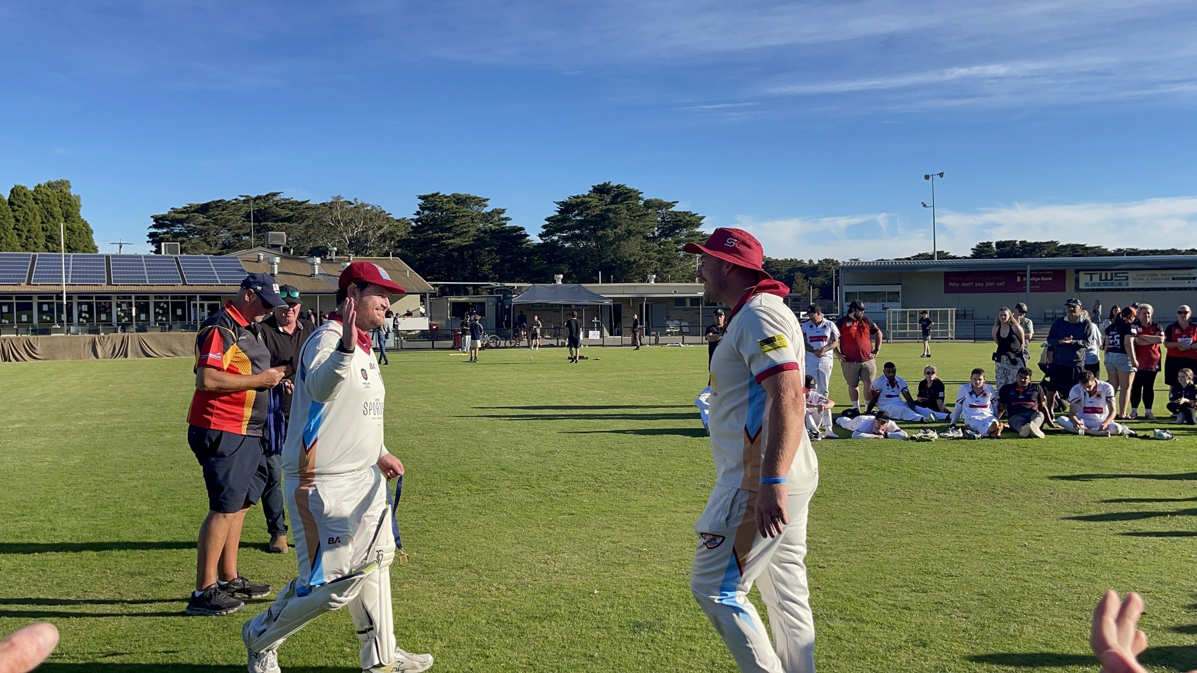 NDCC cricketers in whites greeting teammates and supporters on the oval after the grand final.