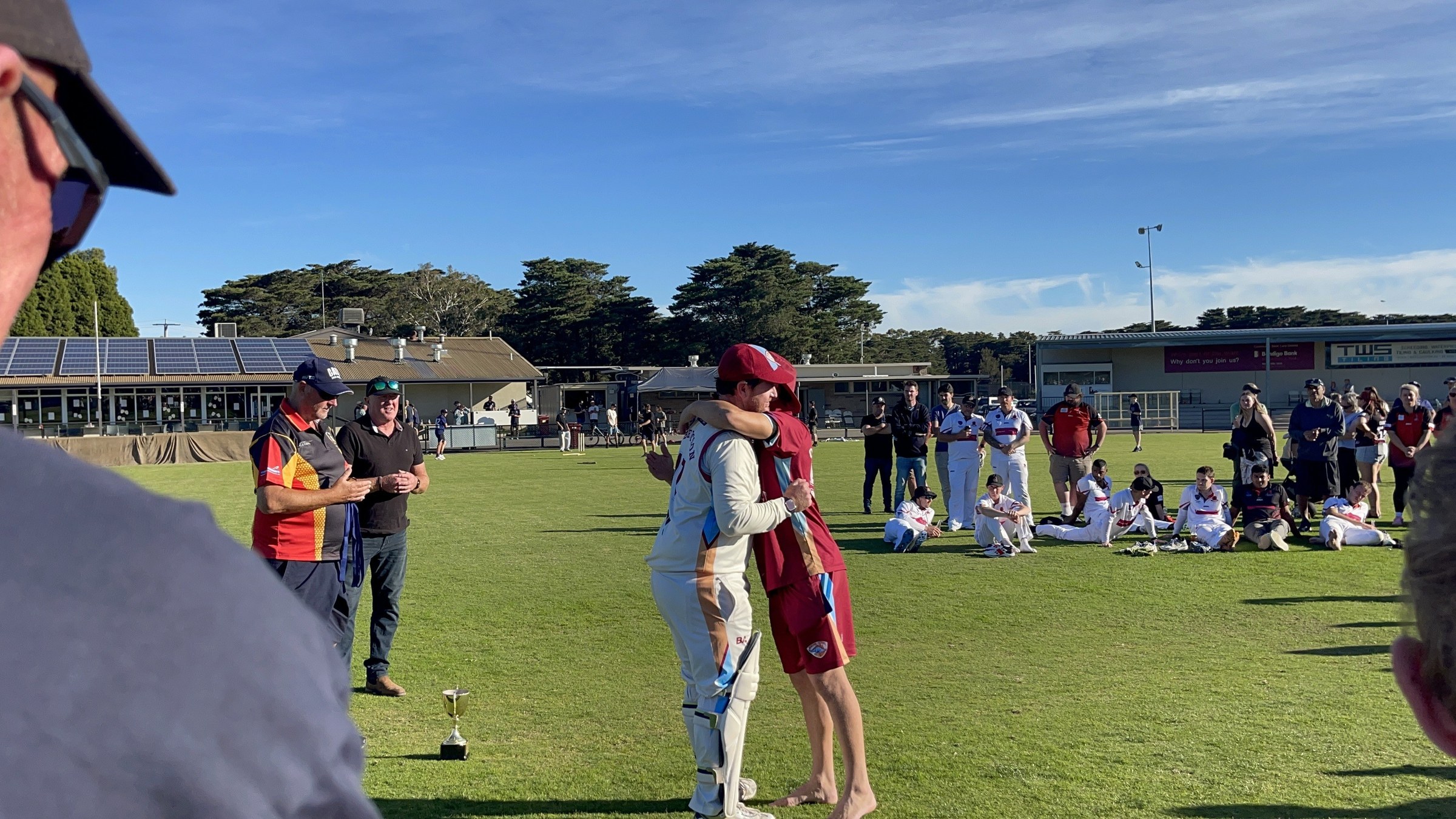 NDCC cricketers in whites greeting teammates and supporters on the oval after the grand final.