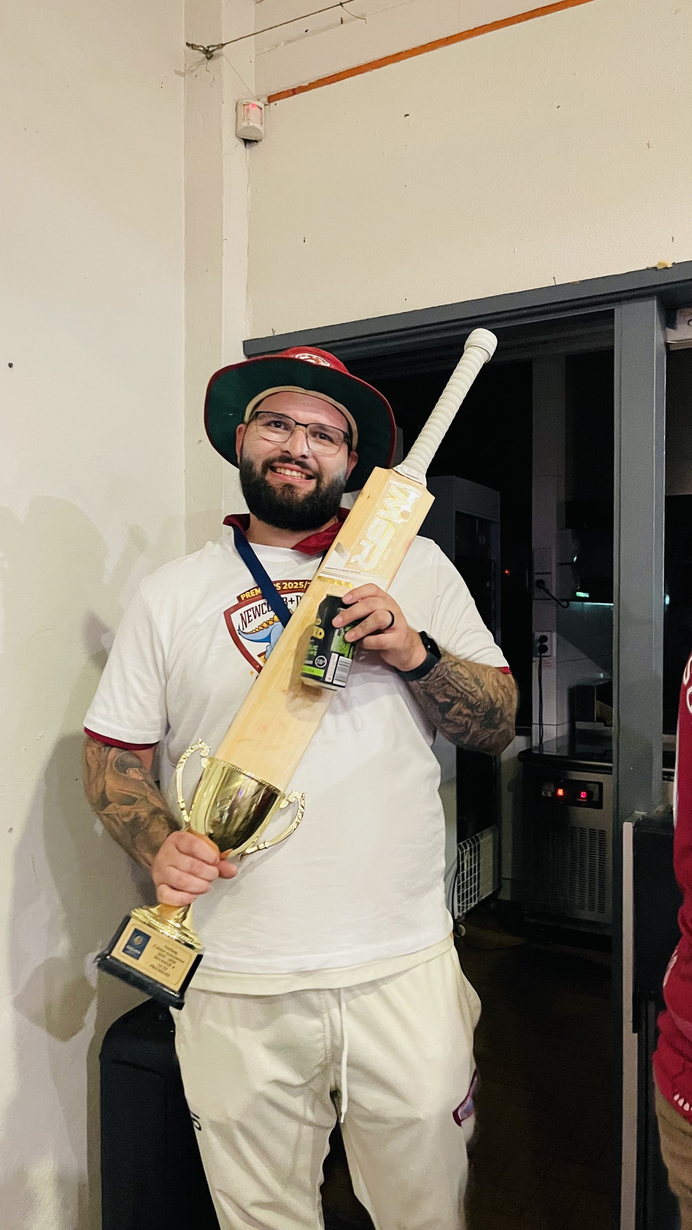 A cricketer in whites holding a bat during the evening premiership celebrations.