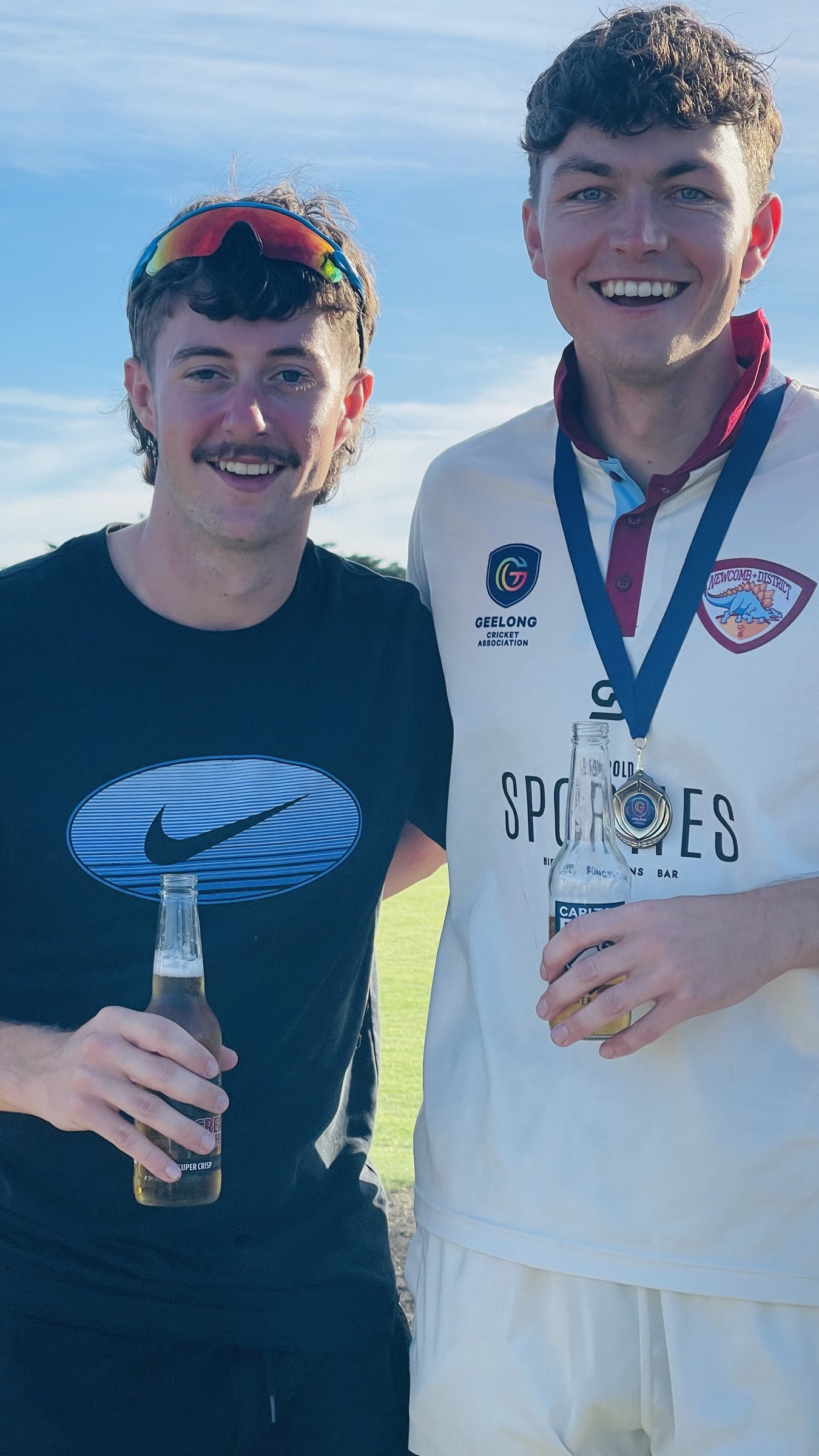 A premiership player wearing a medal and a supporter posing together on the oval.