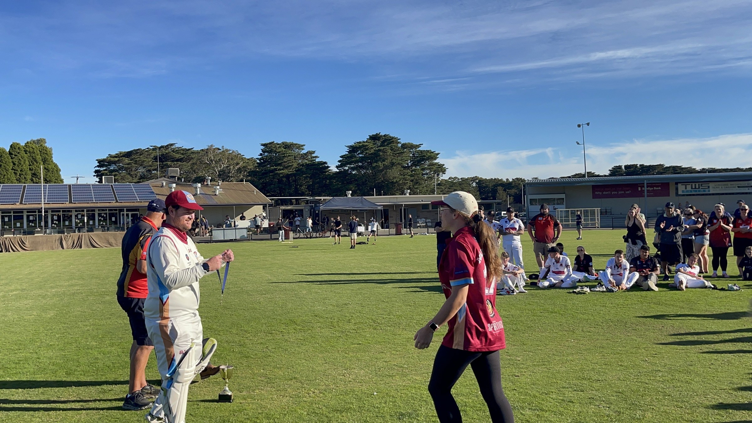 NDCC cricketers in whites greeting teammates and supporters on the oval after the grand final.