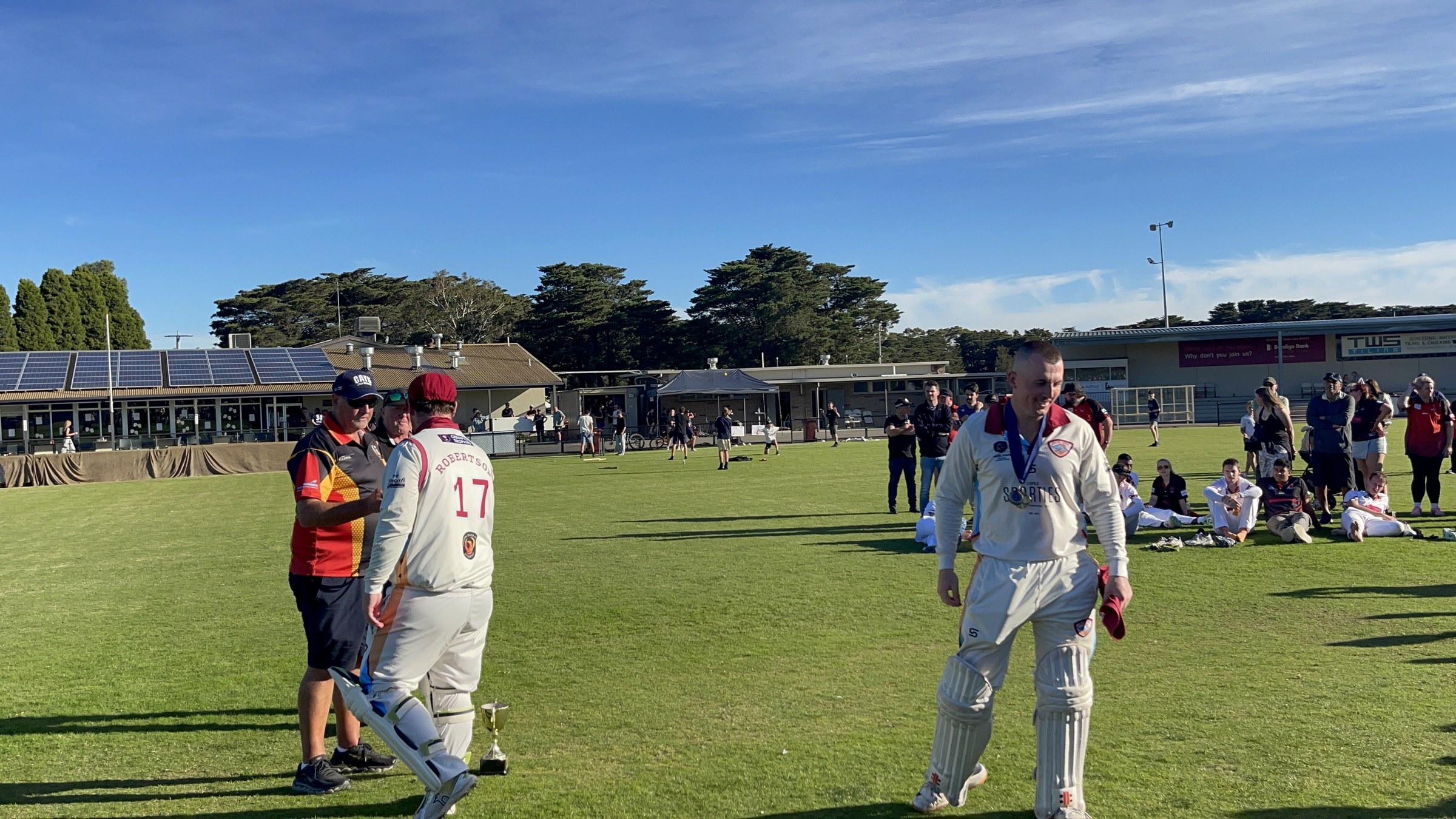 NDCC cricketers in whites greeting teammates and supporters on the oval after the grand final.