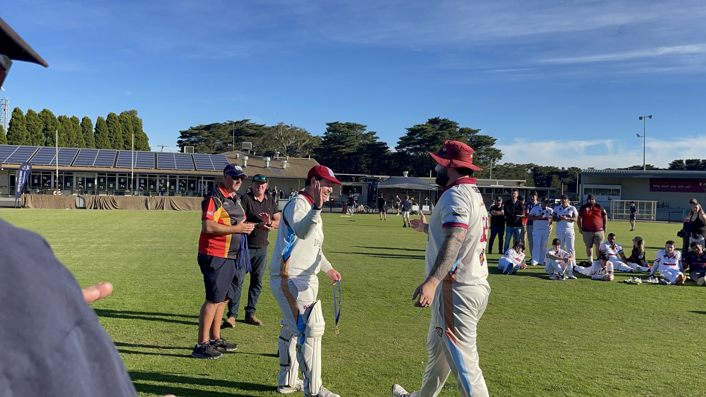 NDCC cricketers in whites greeting teammates and supporters on the oval after the grand final.